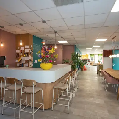 Bright office space to rent at Boddenkampsingel 95, Enschede, featuring a furnished interior with a long table, bar stools, and colorful decor, ideal for workspaces.