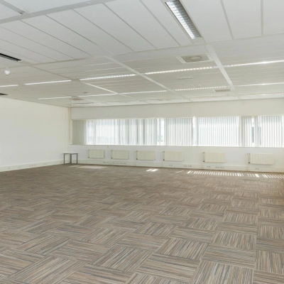 Spacious unfurnished office interior with neutral carpet and large windows, suitable for office space rental at Brandweerstraat 20-30, Enschede. Abundant natural light enhances the open, professional environment.