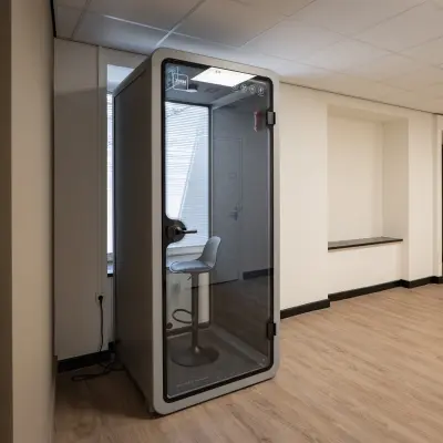 Office space for rent at Kuipersdijk 2-4 in Enschede featuring a quiet phone booth with a stool, ideal for private calls.