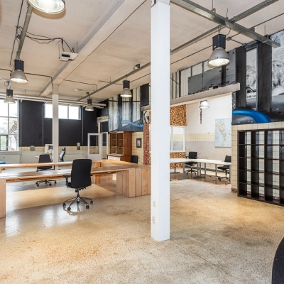 Modern office space rental at Rigtersbleek-Zandvoort 10, Enschede, featuring an open floor plan with desks and chairs, industrial lighting, and large windows.