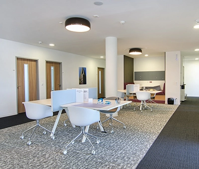 Modern furnished office space at Mergenthaler Allee 15-21 in Eschborn, featuring sleek desks with chairs and a comfortable seating area, ideal for office space rental.