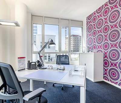 Bright office space with a desk, chair, and vibrant patterned wall, perfect for office space rental at Mergenthaler Allee 15-21, Eschborn.
