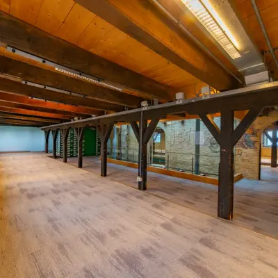 Spacious open office space with wooden beams and carpeted flooring at Prins Hendrikkade 3, ideal for office space rental in Franeker.