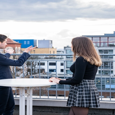 Three people at a rooftop table discussing business with a view of Frankfurt East skyline.