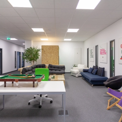 Bright workspace with couches, a table, a pool table, and wall art in Frankfurt West, ideal for office space rental.