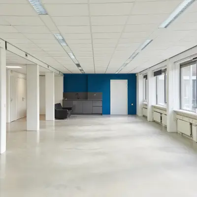 Bright, unfurnished office space at Schweitzerlaan 12, Groningen, featuring large windows and a small kitchenette area, perfect for office space rental.
