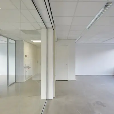 Bright, unfurnished office space available for rent at Schweitzerlaan 12, Groningen with large windows and glass partitions.
