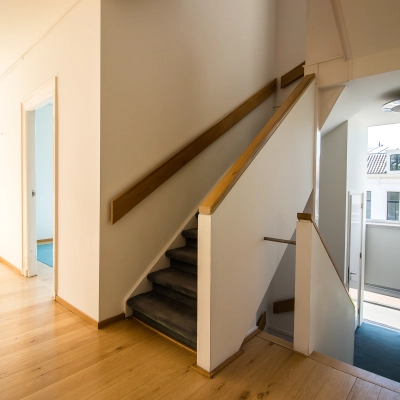 Bright interior view of an unfurnished office space available for rent at Prinsen Bolwerk 1, Haarlem Centraal Station, featuring wooden floors, large windows, and a staircase.