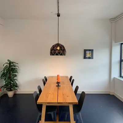 Bright, minimalist meeting room in Haarlem Oost with a long wooden table and eight chairs, suitable for office space rental.
