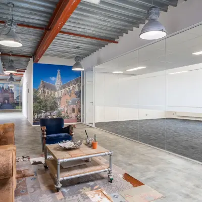 Spacious office interior at Bingerweg 18A-18R in Haarlem Waarderpolder, featuring modern lighting, a glass-enclosed room, and cozy seating area. Ideal for office space rental.