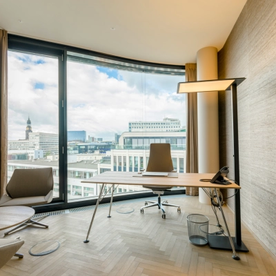 Modern office space with a desk, two chairs, and a panoramic window view in Hamburg Neustadt, perfect for office space rental.
