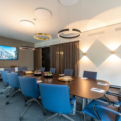 Modern conference room with a large table, blue chairs, and a TV on the wall, suitable for office space rental in Hamburg Old Town.