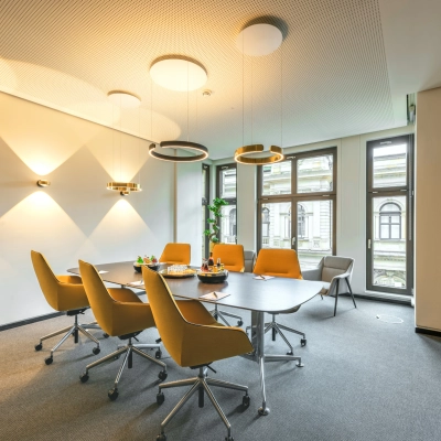 Modern office space for rent at Alter Wall 32, Hamburg Old Town, featuring a furnished conference room with a large table and chairs under stylish lighting.