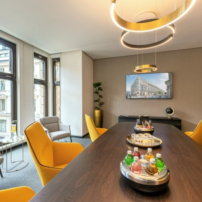 Bright office space on Alter Wall 32, Hamburg Old Town, featuring a large table, colorful chairs, and a city view. Ideal office space rental for meetings.