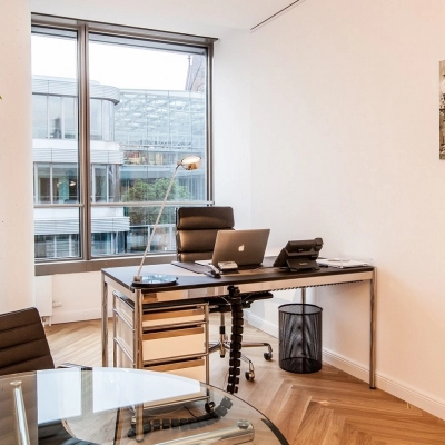 Bright office space rental in Hamburg Old Town at Ballindamm 39 featuring modern furnishings and a large window with city views.