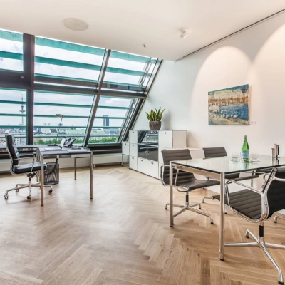 Bright office to rent at Ballindamm 39 with modern furnishings, featuring sleek desks and an impressive view through slanted windows, perfect for office space rental in Hamburg Old Town.