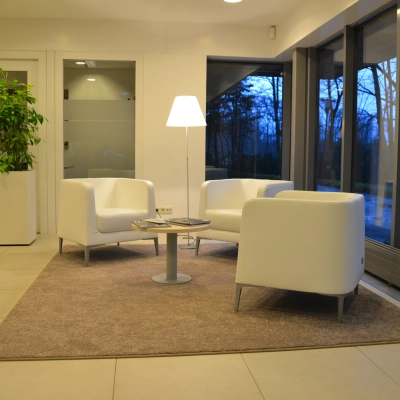 Modern office space at Herenweg 115, Heemstede, featuring a cozy seating area with white chairs and a lamp, ideal for office space rental.