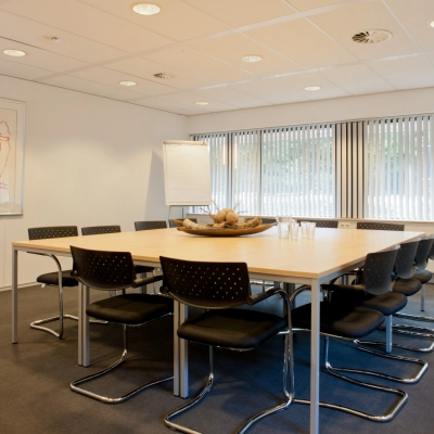 Conference room at Herenweg 115, Heemstede, featuring a large table, modern chairs, and artwork, ideal for office space rental.
