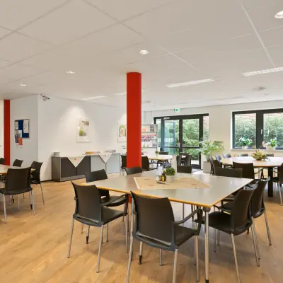 Bright office space at Welbergweg 60 in Hengelo featuring wooden floors, tables, chairs, and potted plants, ideal for office space rental.