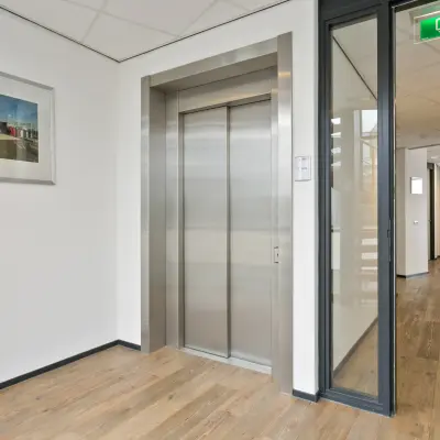 Interior view of an office space at Welbergweg 60, Hengelo featuring a modern elevator and hallway, suggesting office space rental opportunities.