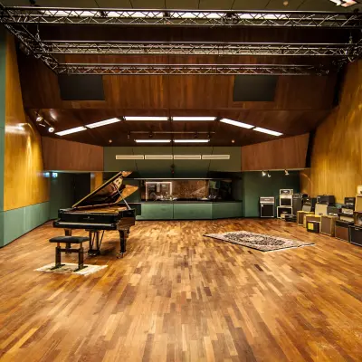 Spacious, furnished office space rental at Catharina van Renneslaan 8-10, Hilversum, featuring a grand piano and sound equipment in a well-lit open area.