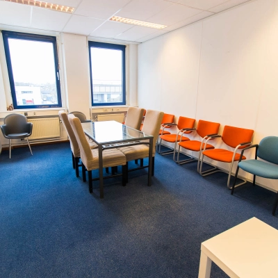 Office space rental at Franciscusweg 219, Hilversum. The room features a table with chairs, perfect for meetings or collaborative work. Large windows provide ample natural light, illuminating the office to rent.