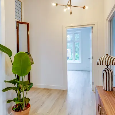 Bright, stylish hallway at Graaf Florislaan 40, Hilversum, suitable for office space rental, featuring modern decor with wooden flooring and indoor plants.