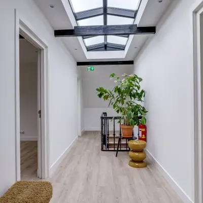Bright, modern interior hallway at Graaf Florislaan 40, ideal for office space rental with a skylight and plants adding a touch of nature.