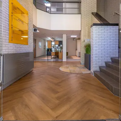 Entrance at Mozartlaan 27 office building in Hilversum, featuring modern flooring and signage, ideal for office space rental.