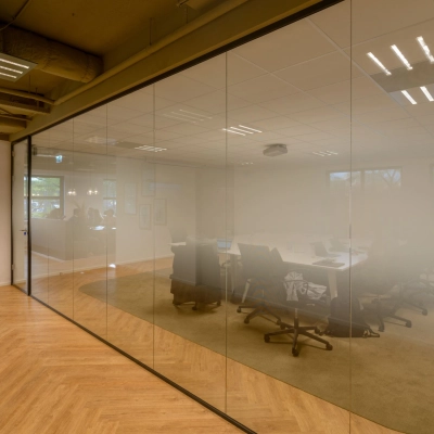 Spacious conference room at Olympia 1 in Hilversum with glass walls and modern furnishings, perfect for office space rental.