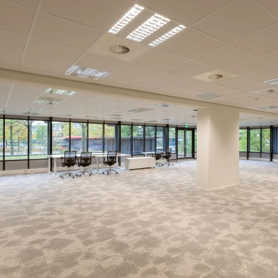 Interior view of an unfurnished office space for rent at Olympia 1, Hilversum, featuring large windows and ample floor area ideal for customization.