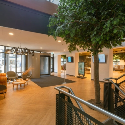Spacious office reception with modern seating and a decorative tree at Olympia 1, Hilversum, ideal for office space rental.