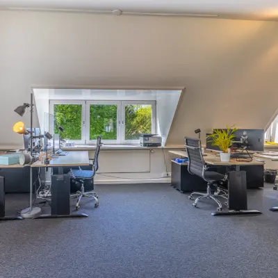Bright office space at Utrechtseweg 47, Hilversum with modern desks and chairs, ideal for office space rental. Large windows provide natural light.