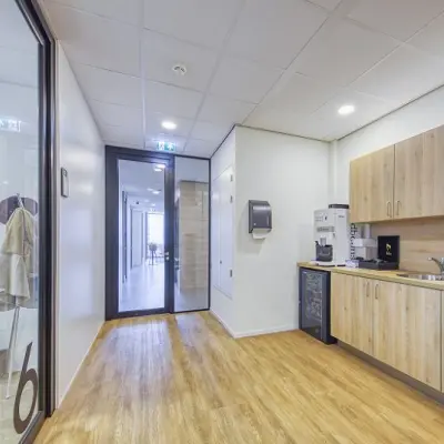 Spacious office pantry at Polarisavenue 130-150, Hoofddorp features wood flooring, cabinets, sink, and coffee machine, ideal for office space rental.