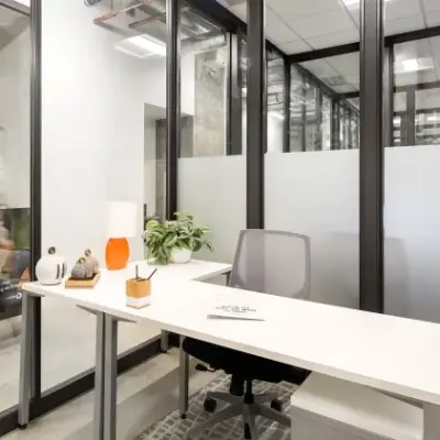Modern office space at Siriusdreef 17, Hoofddorp with sleek furnishings and glass partitions, ideal for rent office space enthusiasts. A person is walking past, adding a dynamic touch to the office environment.