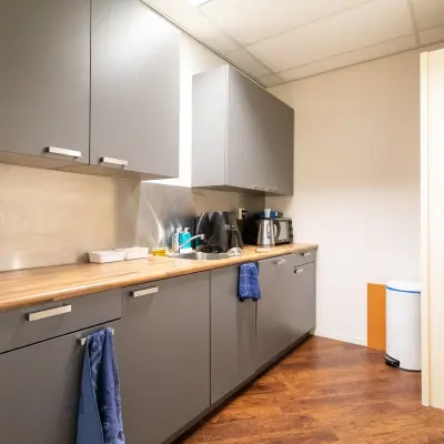 Cozy pantry space at Sandtlaan 36, Katwijk, equipped with storage cabinets, a coffee maker, and a dishwasher, perfect for office space rental.