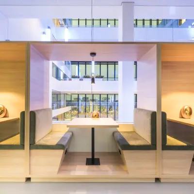Modern office space with wooden booths for rent at Bargelaan 200, Leiden, featuring ambient lighting and glass wall views.