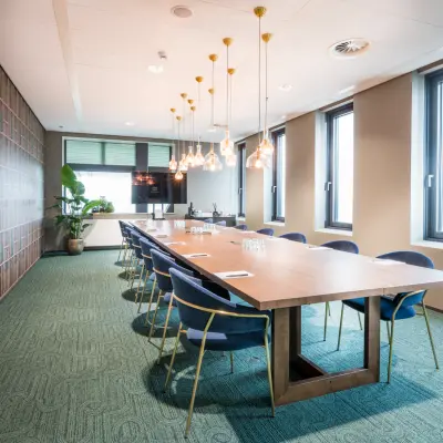 Modern conference room at Bargelaan 200, Leiden, showcasing a long table with elegant chairs, ideal for office space rental. Large windows provide natural light.
