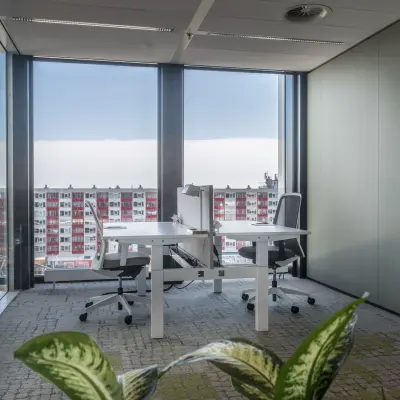 Modern office space rental at Bargelaan 200, Leiden, featuring large windows and two desks with chairs, overlooking the cityscape.