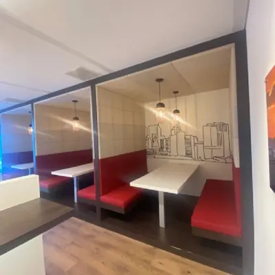 Furnished office space for rent at Mendelweg 30 in Leiden, featuring cozy booths with red seating and cityscape artwork.