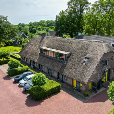 Exterior view of office space at Hamersveldseweg 120, Leusden, featuring a rustic building with a thatched roof and ample parking.