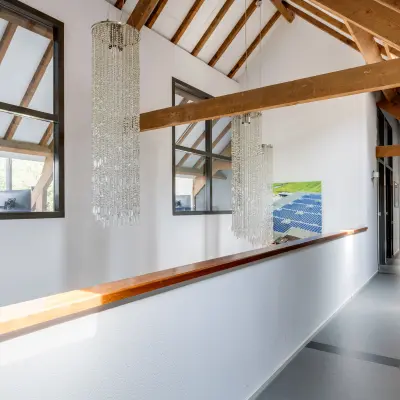 Bright office corridor with wooden beams and chandeliers at Hamersveldseweg 120, Leusden, available for office space rental.