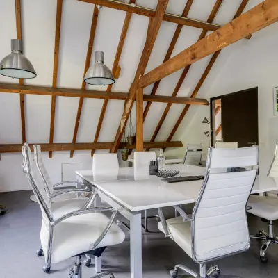 Modern office with exposed beams and sleek furnishings at Hamersveldseweg 120, Leusden, available for office space rental. Spacious seating setup for collaborative meetings.