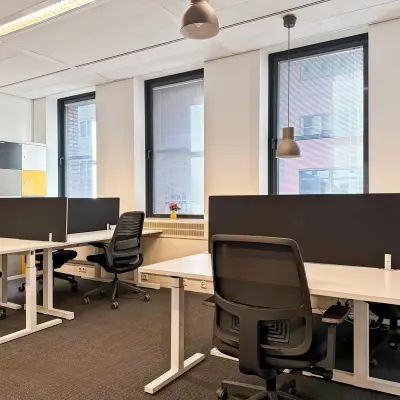 Bright office space with several desks, chairs, and dividers, ideal for those seeking office space rental at Robert Schumandomein 2, Maastricht.