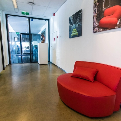Spacious office entrance at Brieltjenspolder 28, Made, featuring a vibrant red couch and art on the walls, ideal for office space rental.