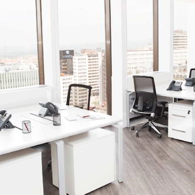 Bright office space at Paseo de la Castellana 141, Madrid Azca, featuring modern desks and chairs with a city view ideal for office space rental.