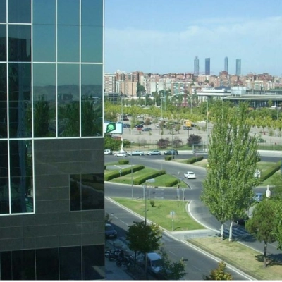 View of the modern office building's exterior with surrounding cityscape at Avenida del Partenón 16-18, ideal for office space rental in Madrid Barajas.