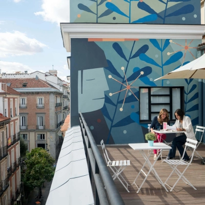 Terrace at calle de las Huertas 11, Madrid Center, with two people collaborating at a table, surrounded by colorful murals. Ideal spot for rent office space discussions.