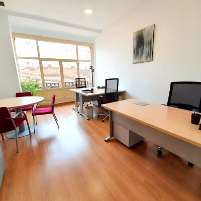 Bright office space with large windows, modern furniture, and two desks at Calle Gran Vía 6, perfect for rent office space in Madrid Center.
