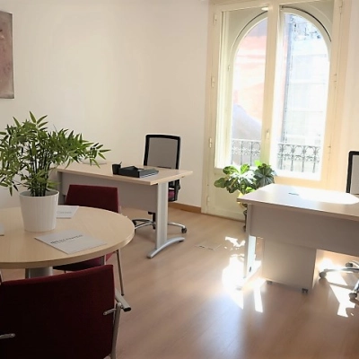 Bright office space for rent in Madrid Center on Calle Gran Vía 6, featuring desks, chairs, and natural light from large windows.